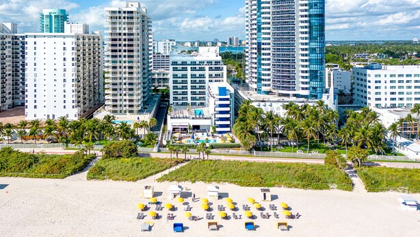 A beach with sun loungers and umbrellas, surrounded by high-rise buildings and palm trees. - Hilton Cabana Miami Beach Resort (Miami Beach)