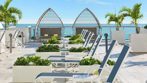 A beachside lounge area with sun loungers and planters, overlooking the ocean. - Hilton Cabana Miami Beach Resort (Miami Beach)