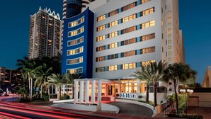 A modern hotel with a prominent Hilton sign, featuring a curved entrance, multiple floors, and a mix of architectural styles. - Hilton Cabana Miami Beach Resort (Miami Beach)