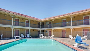 A pool area with lounge chairs and a two-story building with balconies. - Days Inn by Wyndham San Jose (San Jose)