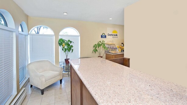 A kitchen with a granite countertop, a chair, and a sign for 'Daybreak Breakfast'. - Days Inn by Wyndham San Jose (San Jose)