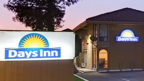 A Days Inn sign and building facade with a clear sky in the background. - Days Inn by Wyndham San Jose (San Jose)