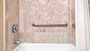 A bathroom with a marble wall, a bathtub, and a grab bar. - Days Inn by Wyndham San Jose (San Jose)