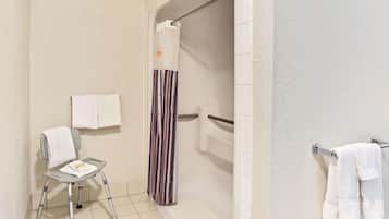 Un baño con ducha, inodoro y una silla con toalla.
