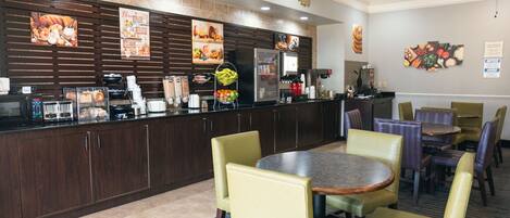 A restaurant with a counter, chairs, and tables.