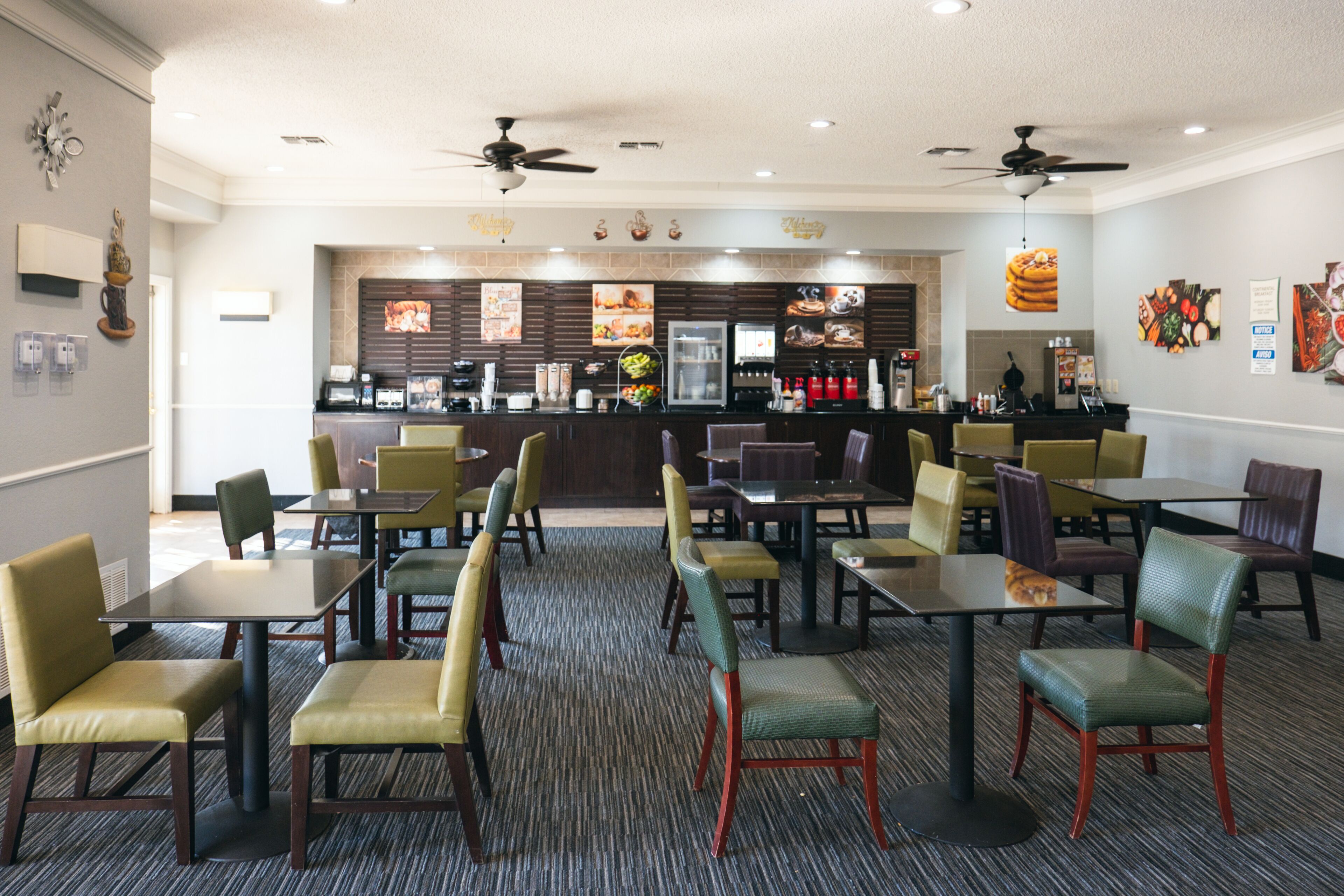 A restaurant with multiple tables and chairs, a counter with a menu, and ceiling fans.