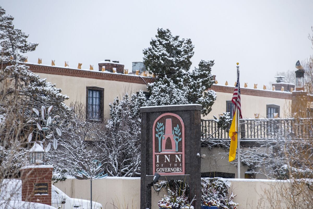 The entrance to the Inn of the Governors with a snow-covered landscape and an American flag.