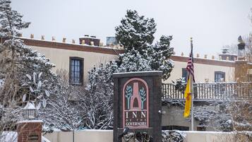 The entrance to the Inn of the Governors with a snow-covered landscape and an American flag.