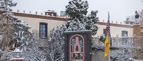 The entrance to the Inn of the Governors with a snow-covered landscape and an American flag.