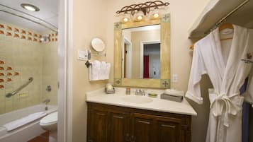 A bathroom with a bathtub, a sink, a mirror, and a robe hanging on a rack.