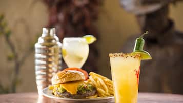 A meal consisting of a hamburger, fries, and a margarita on a table.