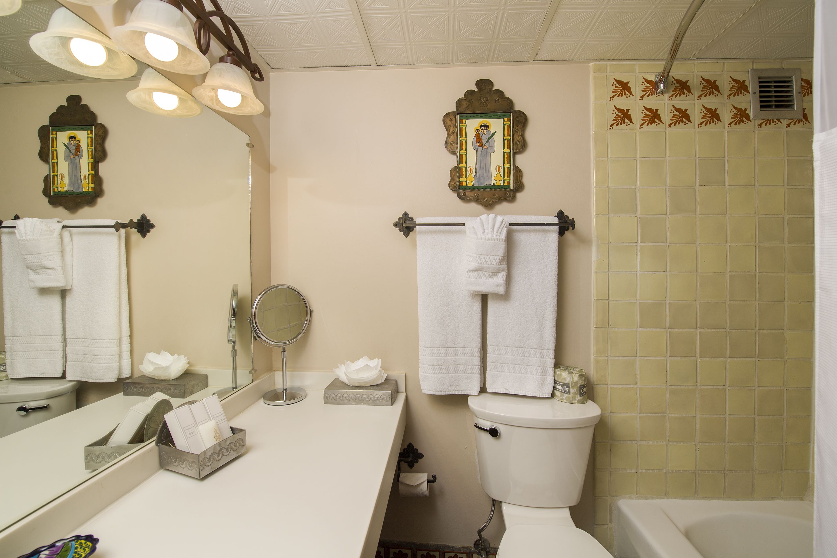 Une salle de bain équipée de toilettes, d’un lavabo, d’un miroir et d’un porte-serviettes.