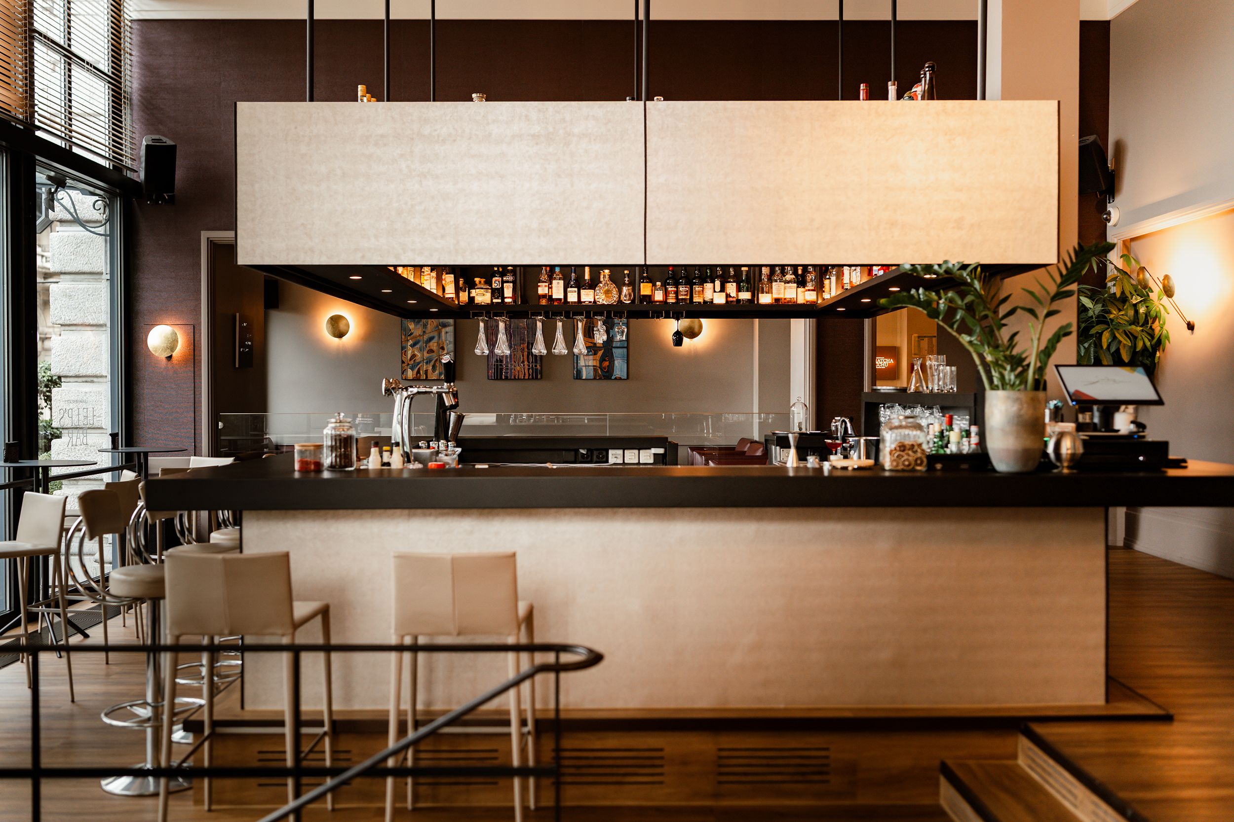 A bar area with a counter, bar stools, and a variety of bottles.