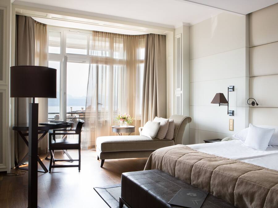Ett hotellrum med en säng, ett skrivbord, en stol och utsikt över omgivningarna.