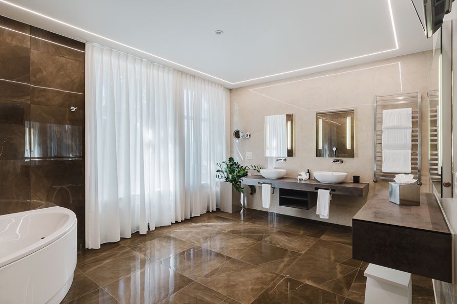 A modern bathroom with a bathtub, two sinks, and a large mirror.