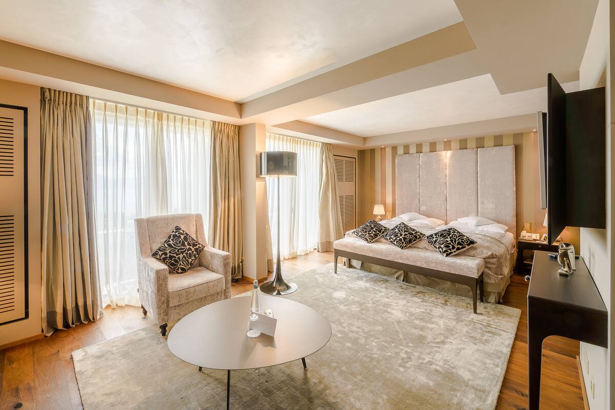 Una habitación de hotel moderna con cama, sofá, mesita de centro y televisión.