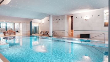 Una piscina techada, sillones reclinables de piscina