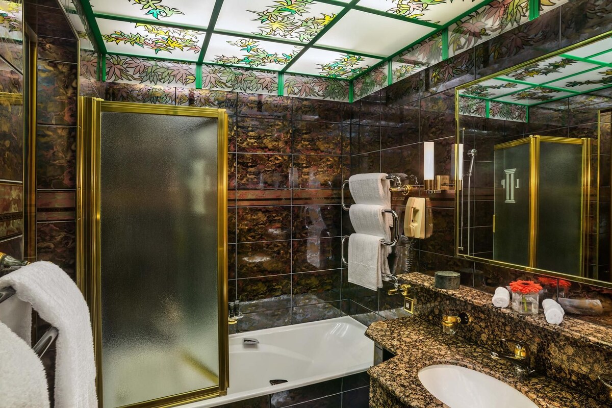 Un baño con un espejo grande, una bañera, un lavamanos y un perchero para toallas.