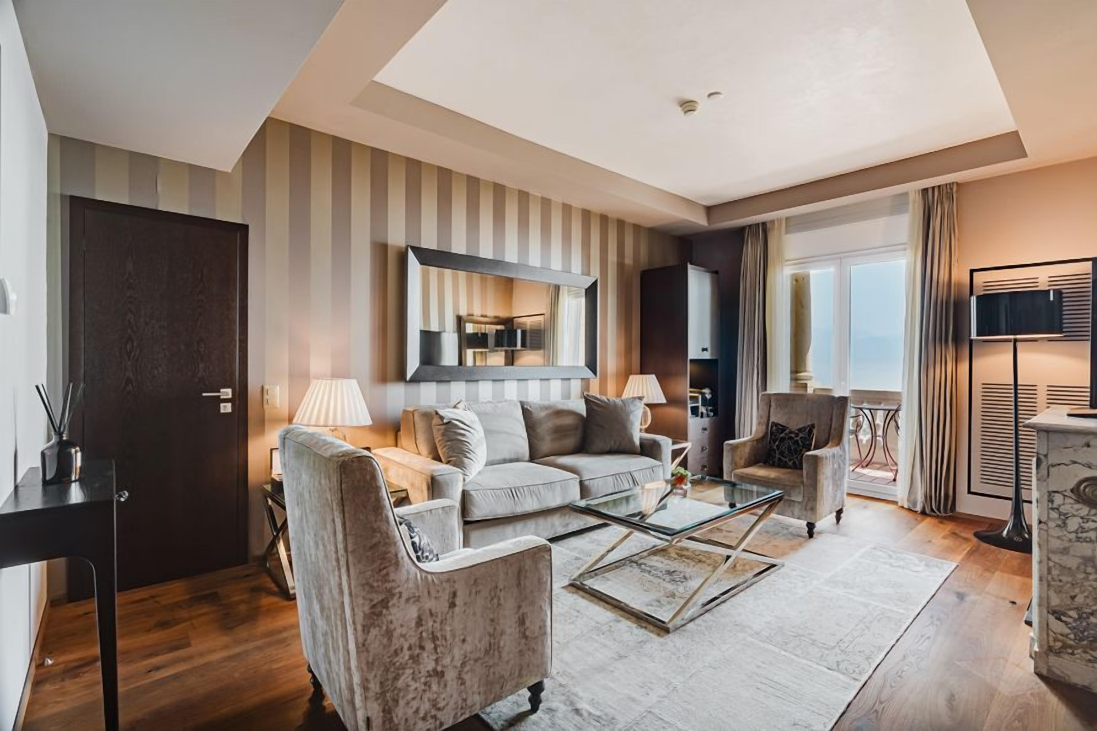 A modern living room with a sofa, armchairs, a coffee table, and a television.