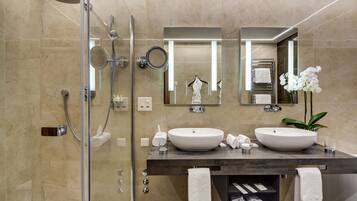 Une salle de bain moderne avec deux lavabos, une douche et un espace de douche séparé par des parois en verre.