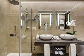 A modern bathroom with two sinks, a shower, and a glass-enclosed shower area.