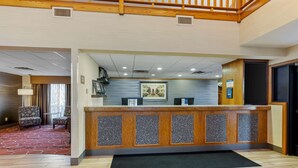 A reception area with a wooden reception desk, a patterned wall, and a carpeted floor. - Best Western Falcon Plaza - Bowling Green (Bowling Green)