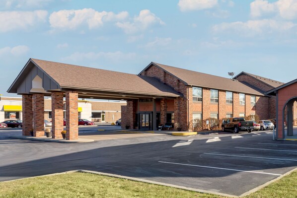 A hotel with a brick facade, a covered entrance, and a parking lot.