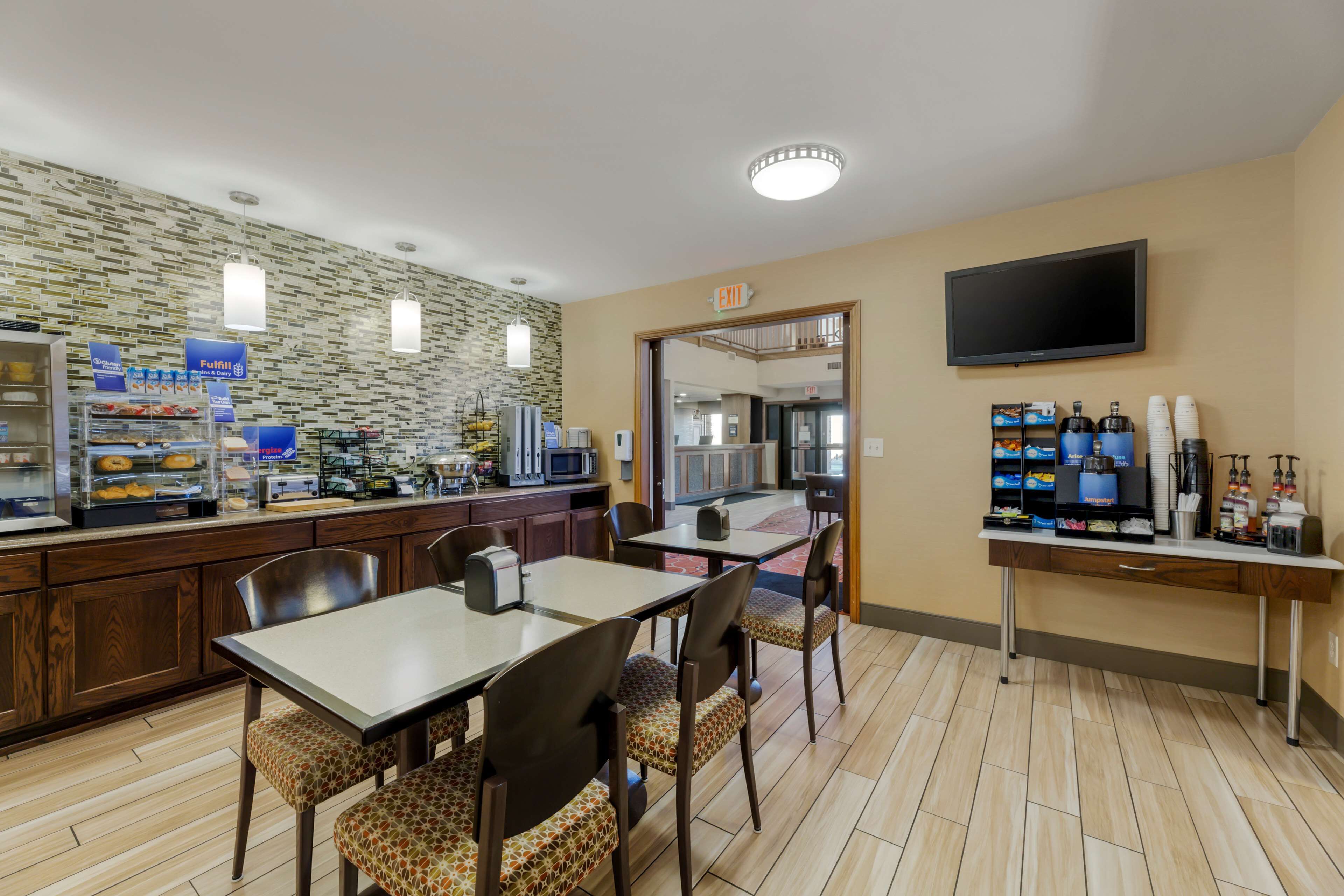 Un hall d’hôtel comprenant un buffet pour le petit-déjeuner, un espace salon et un téléviseur fixé au mur.