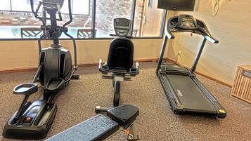 Un gimnasio con cintas de correr, elíptica y banco.