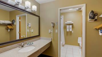 A hotel bathroom with a sink, mirror, hair dryer, and towel rack.