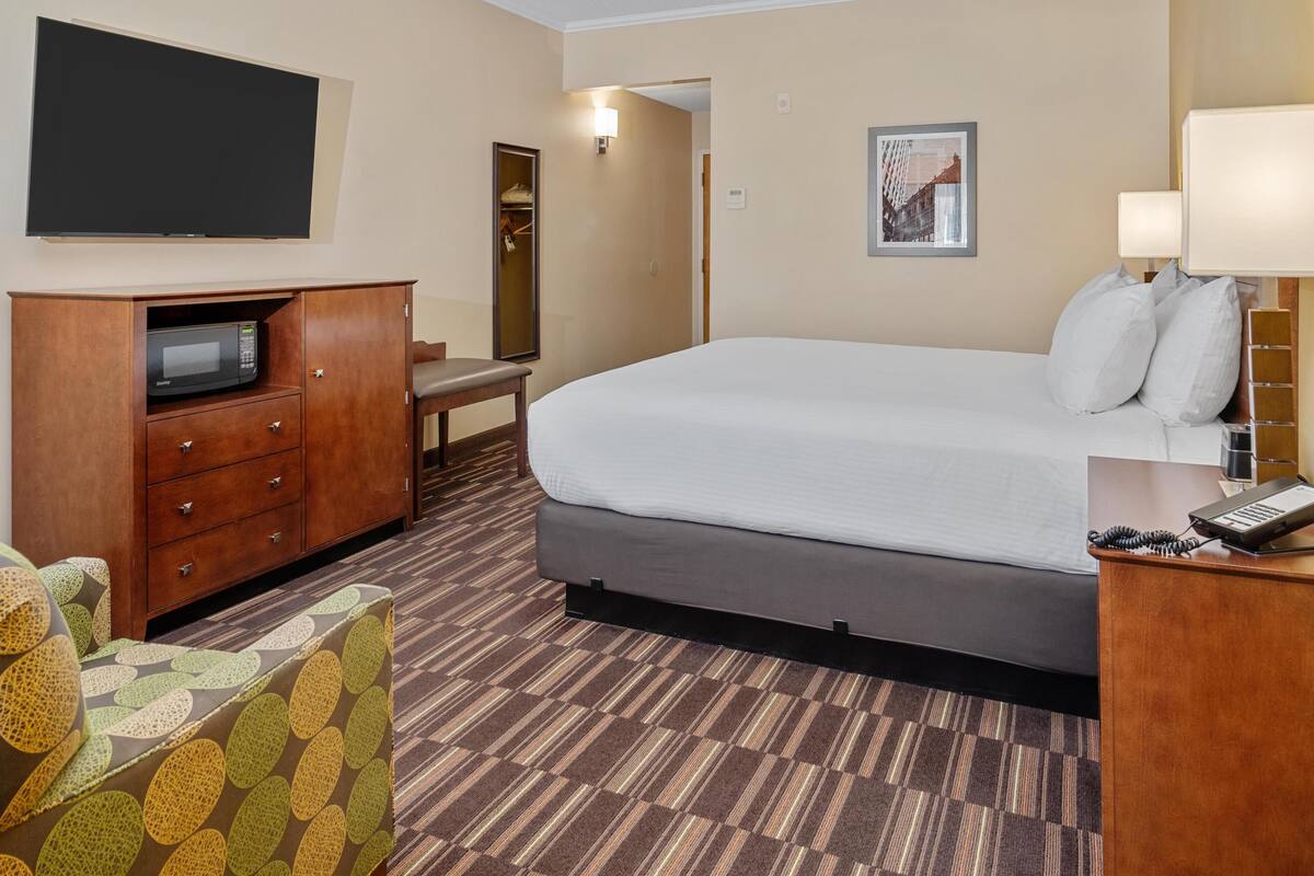 Une chambre d’hôtel équipée d’un lit, d’un bureau avec un téléphone, d’un four à micro-ondes, d’une télévision et d’une chaise.