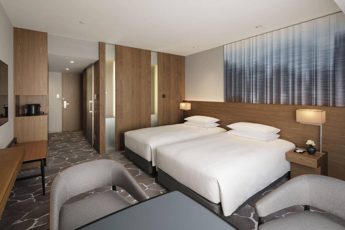 A hotel room with a large bed, two bedside tables, a desk, and a chair.