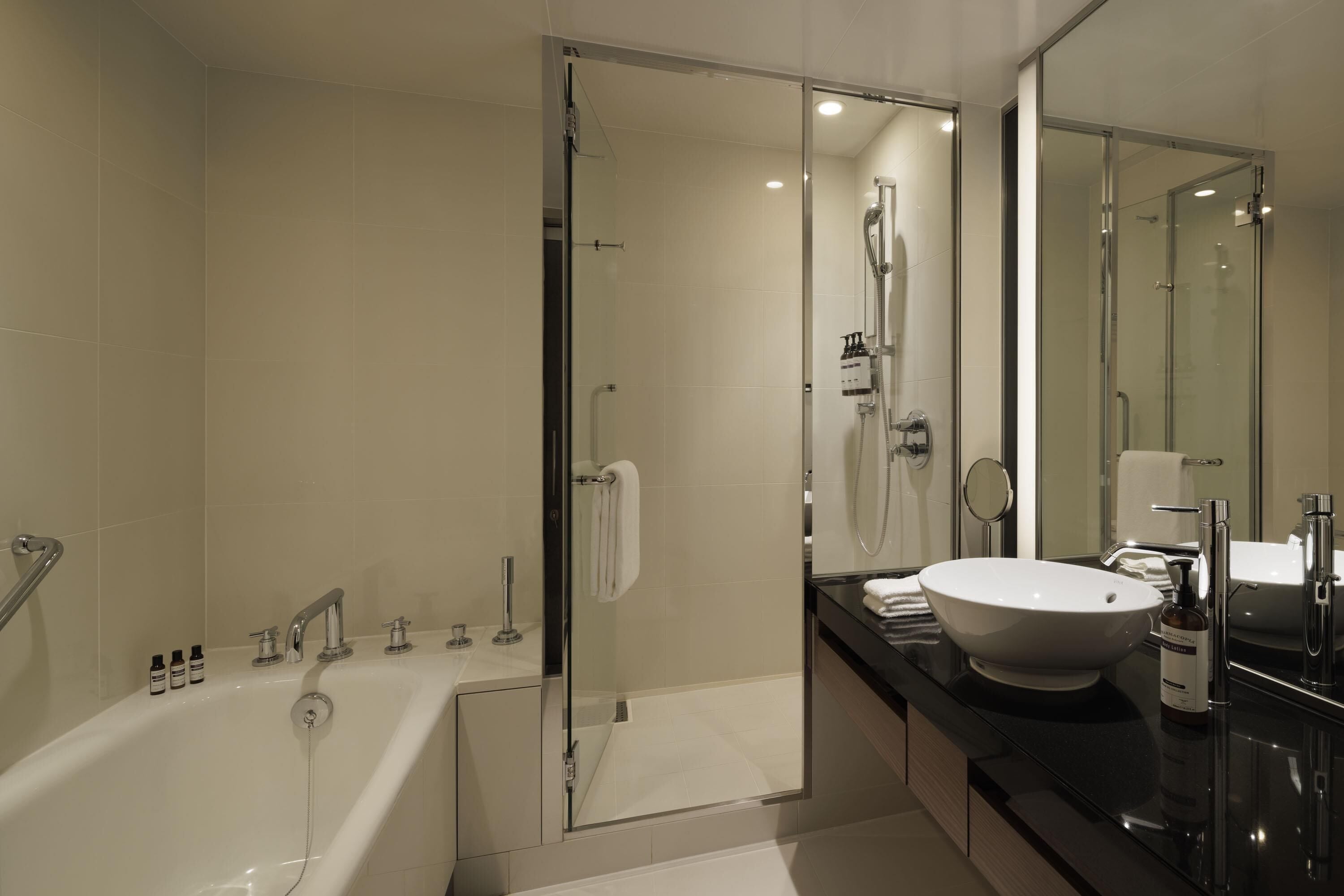 A modern bathroom with a bathtub, shower, and sink.