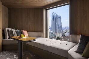 A modern hotel room with a large window, a sofa, a small table with fruits, and a city view. - Hyatt Regency Tokyo (Tokyo)