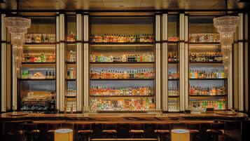 A bar with multiple shelves of liquor bottles, a bar counter, and bar stools.