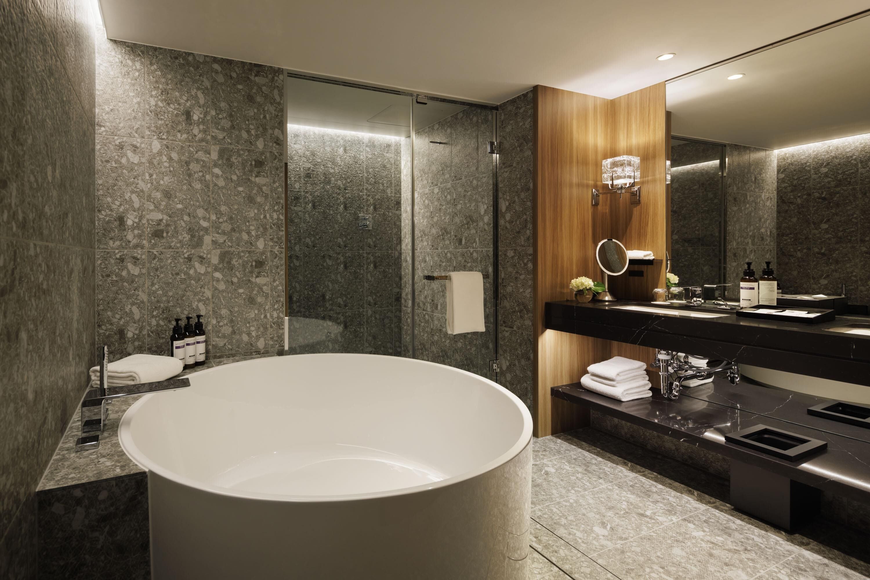 A modern bathroom with a freestanding bathtub, a vanity with a mirror, and a shower area.