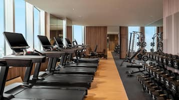 Una palestra con tapis roulant, macchinari per pesi e manubri.