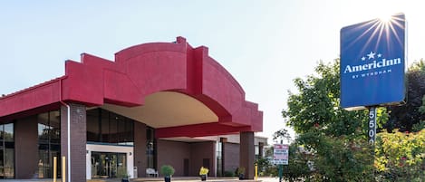 Un hotel con fachada roja, un acceso cubierto y un letrero que dice AmericInn by Wyndham.