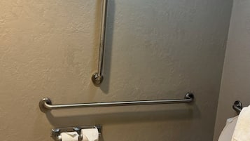 A bathroom with a toilet, grab bars, and a towel rack.