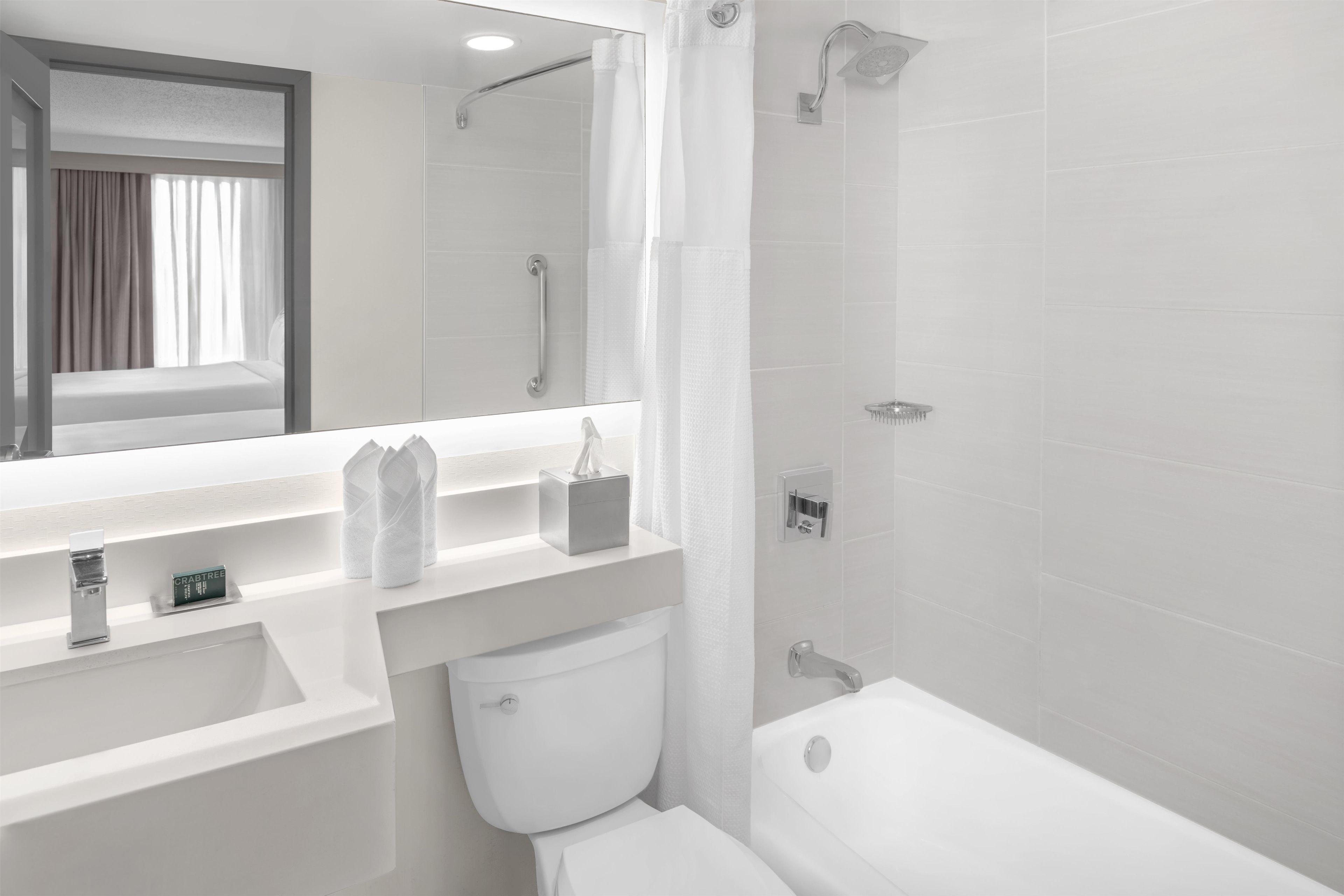 Une salle de bain moderne avec un lavabo, des toilettes et une baignoire, le tout de couleur blanche.