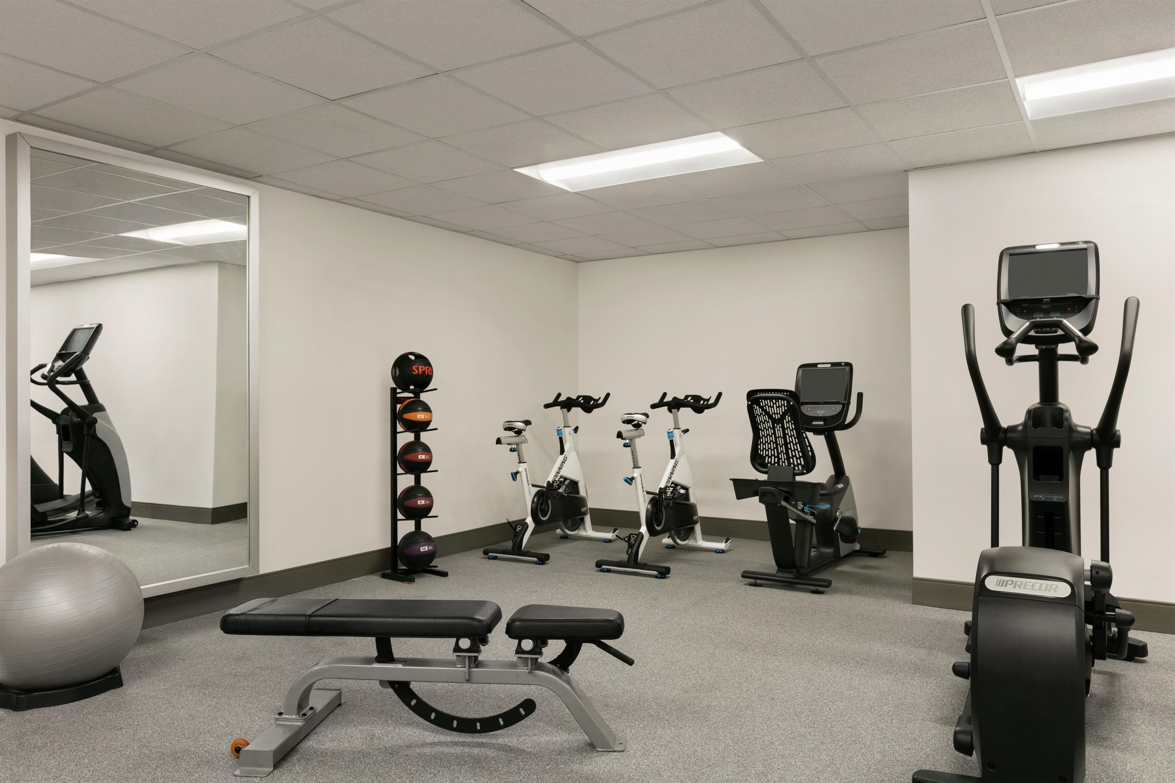 Une salle de sport équipée de divers appareils d’exercice, notamment des tapis de course, des vélos d’appartement et un rameur.