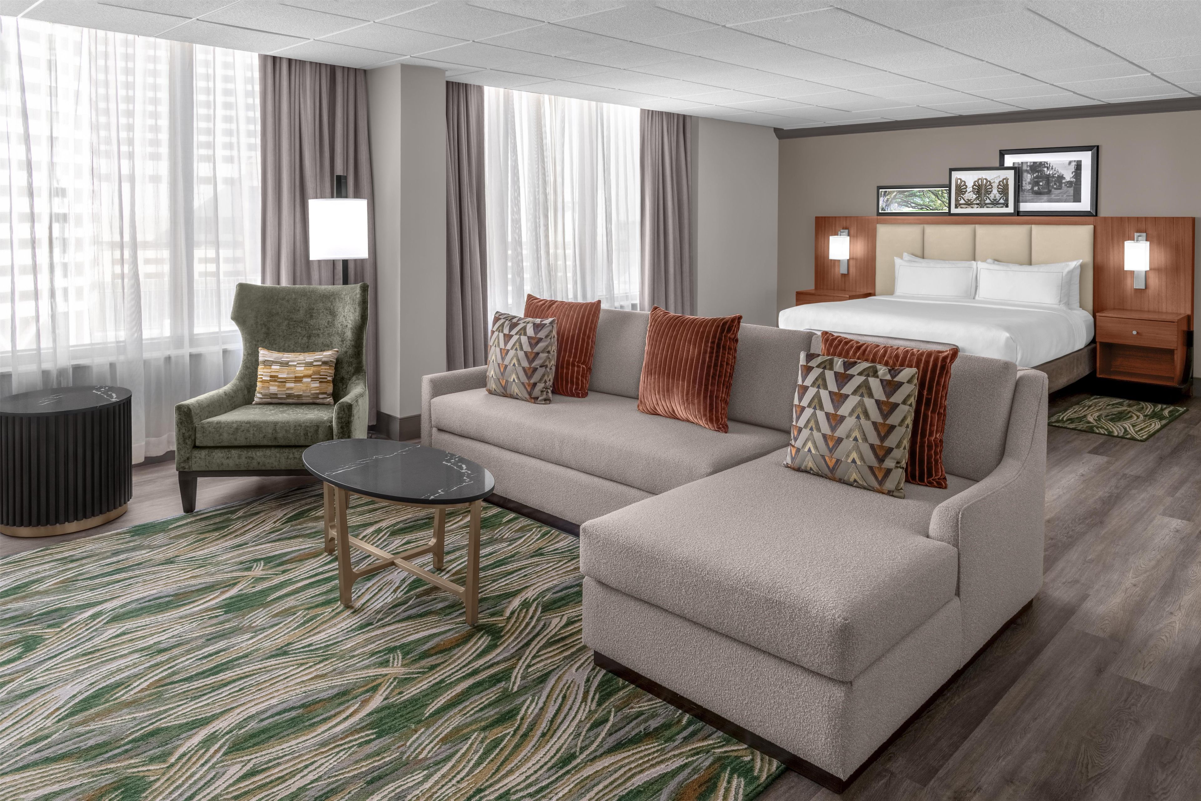 A hotel room with a sofa, armchair, and a small table.