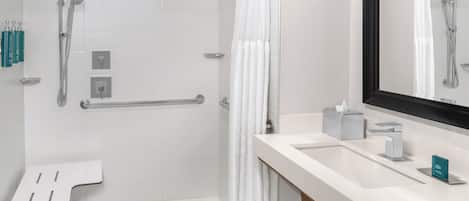 A modern bathroom with a shower, a toilet, a sink, and a mirror.