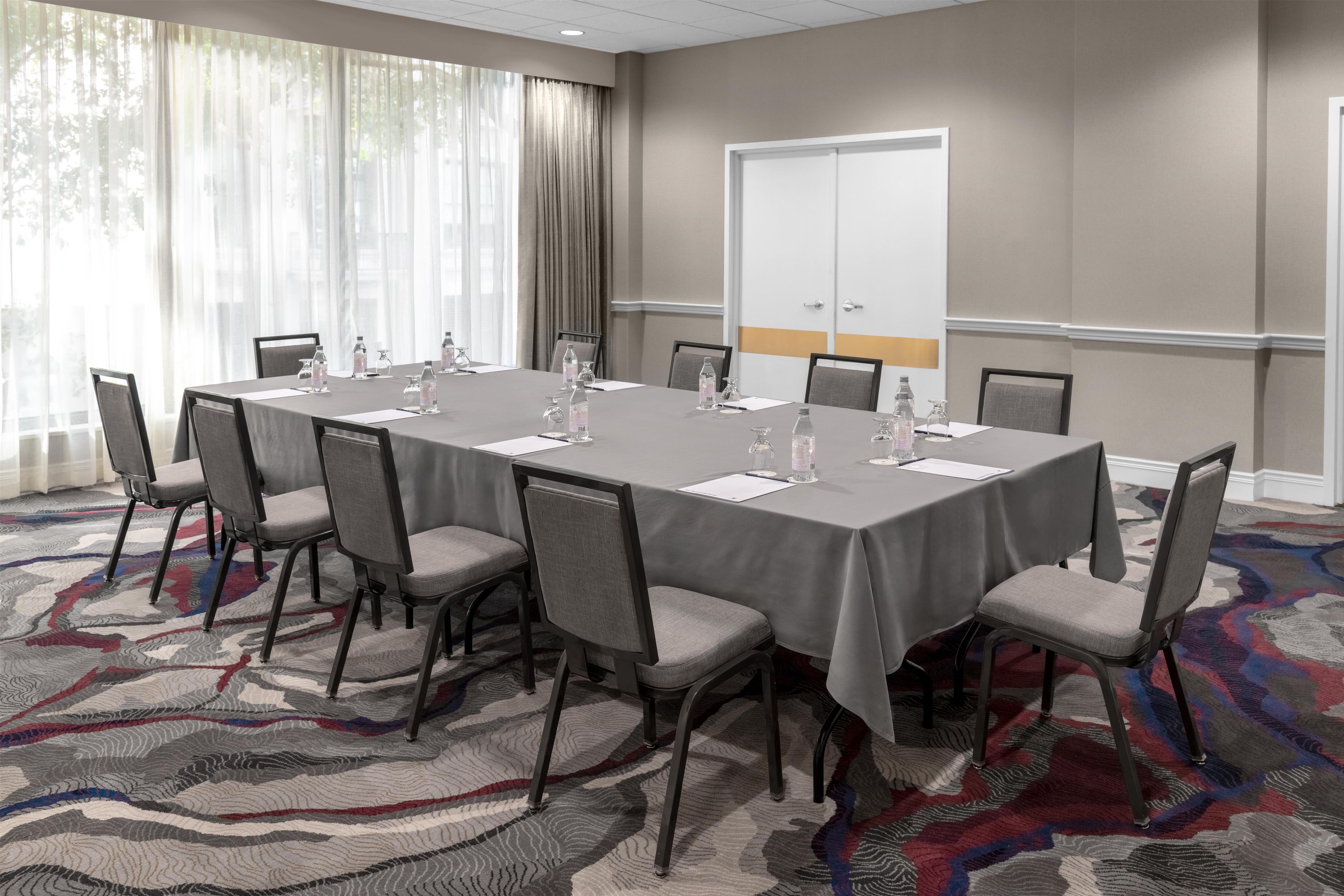 Une salle de conférence avec une longue table, des chaises, des bouteilles d’eau et une porte au fond.