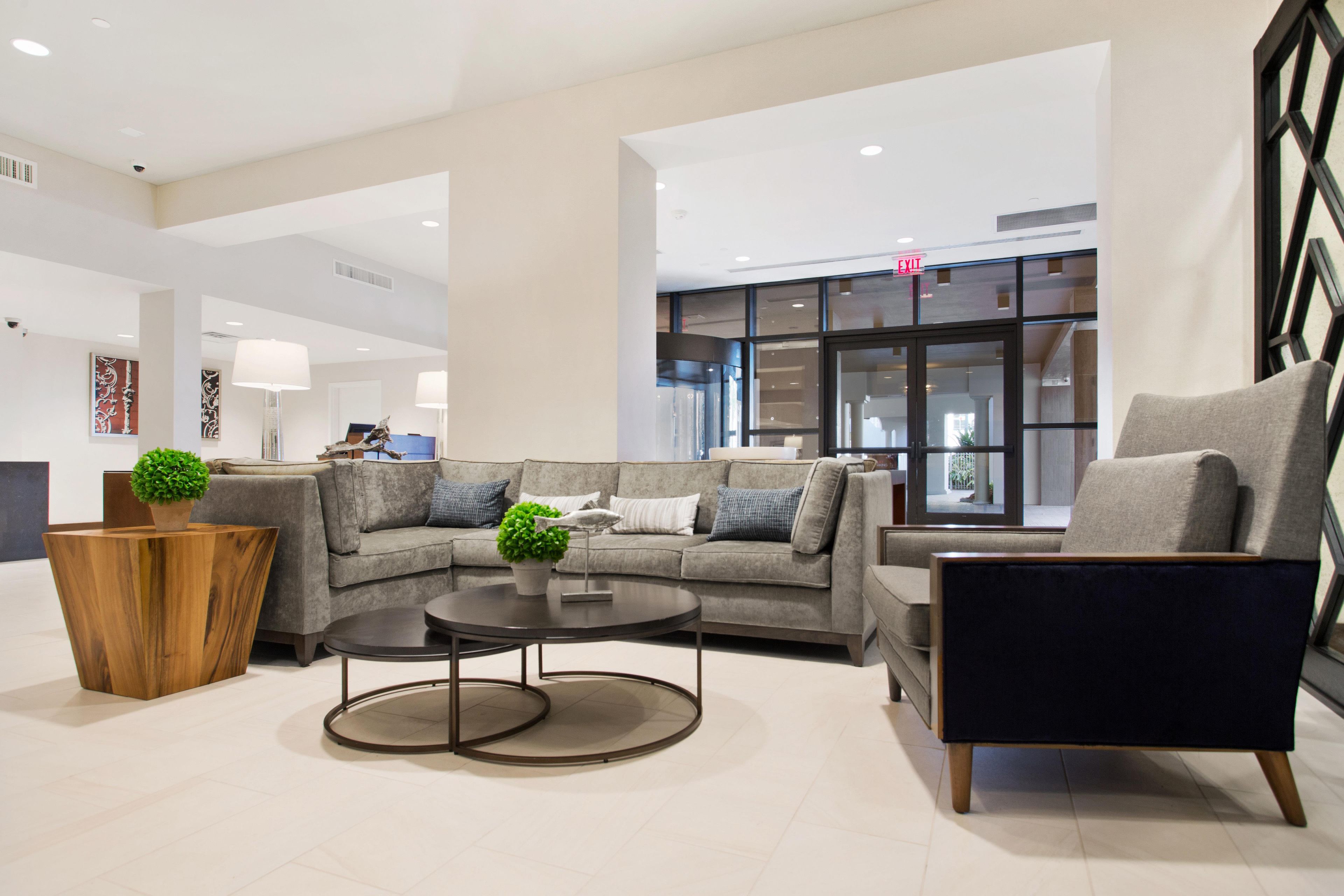 A modern lobby with a sectional sofa, a round coffee table, and a dark armchair.