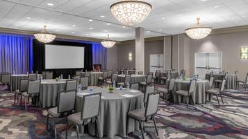 A conference room with round tables, chairs, and a large screen.