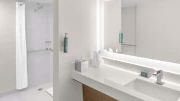 Un baño moderno con ducha, un espejo grande y tocador con lavabo.