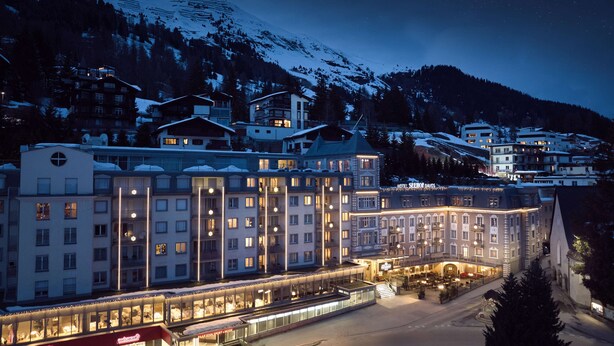 A hotel with multiple floors, large windows, and a central courtyard with outdoor seating.