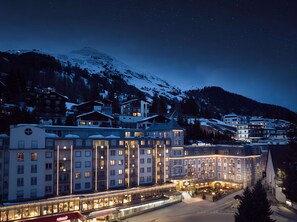 A hotel with multiple floors, large windows, and a central courtyard with outdoor seating. - Hotel Seehof Davos (Davos)