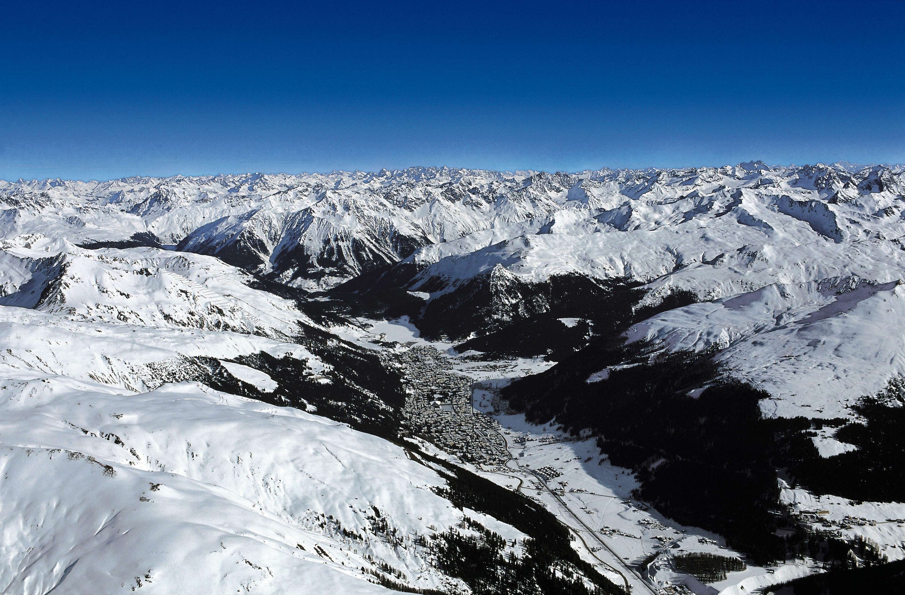 A panoramic view of a snow-covered mountain range with a valley below.